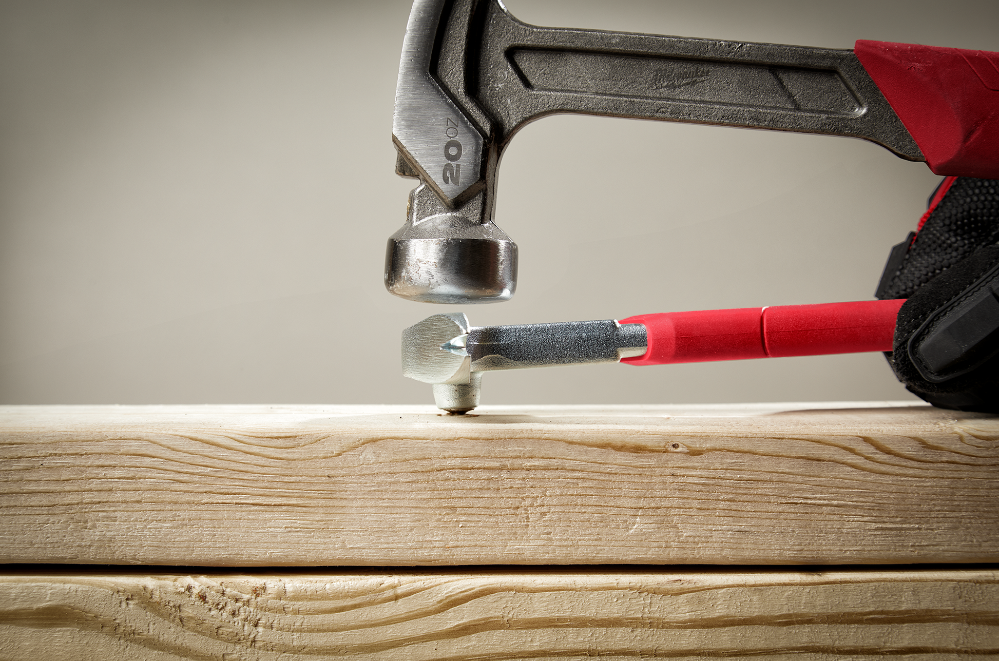 Red-handled nail puller leverages nail removal from wooden board for tools and home improvement tasks