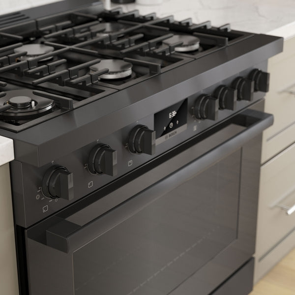 Black stainless steel freestanding gas range with six burners, metal knobs, and digital display in modern kitchen setting