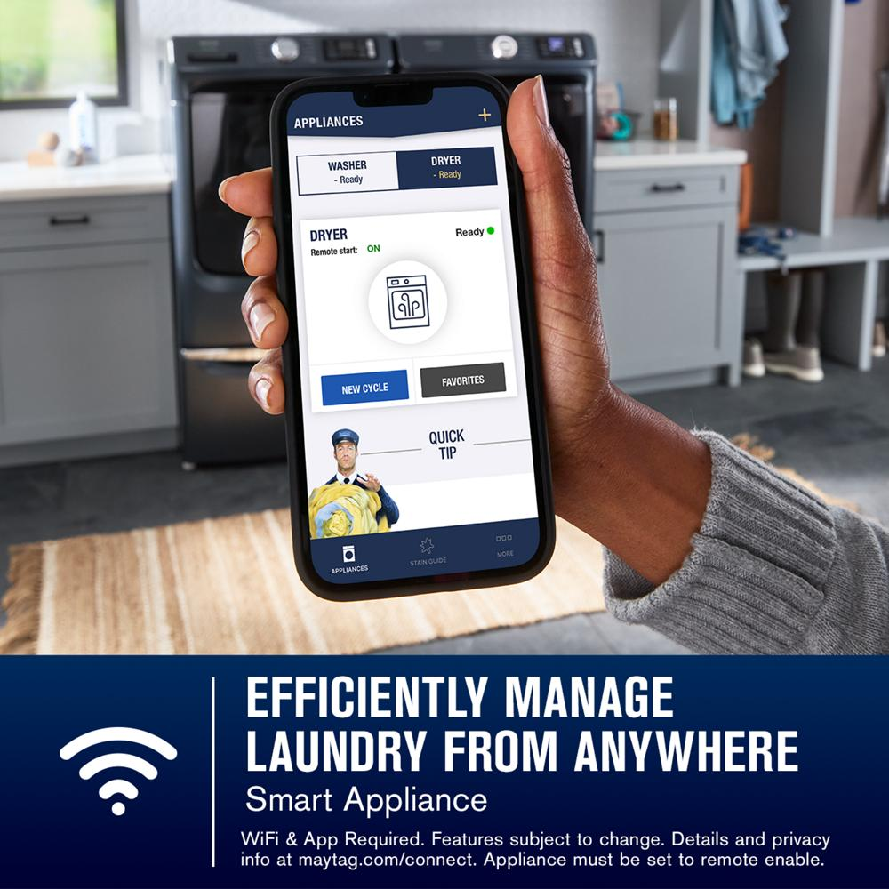 Hand holding smartphone displaying remote control app to manage dryer from washers and dryers collection in kitchen
