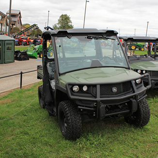 Green full-size crossover utility vehicle with sturdy front guard and wide off-road tires parked on grass outdoors