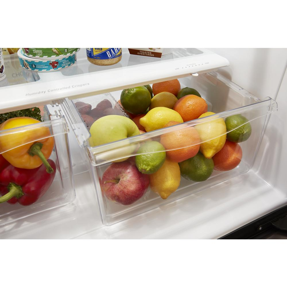 Clear produce drawer in refrigerator filled with assorted fresh citrus fruits and apples in bright kitchen setting