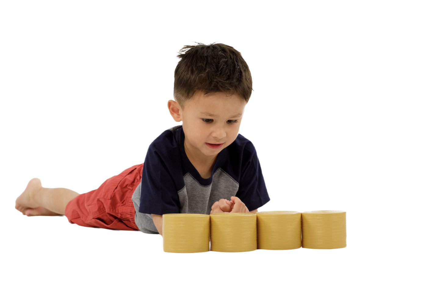 Child lying down inspecting four yellow plastic round bales designed as miniature farming accessories for toy models