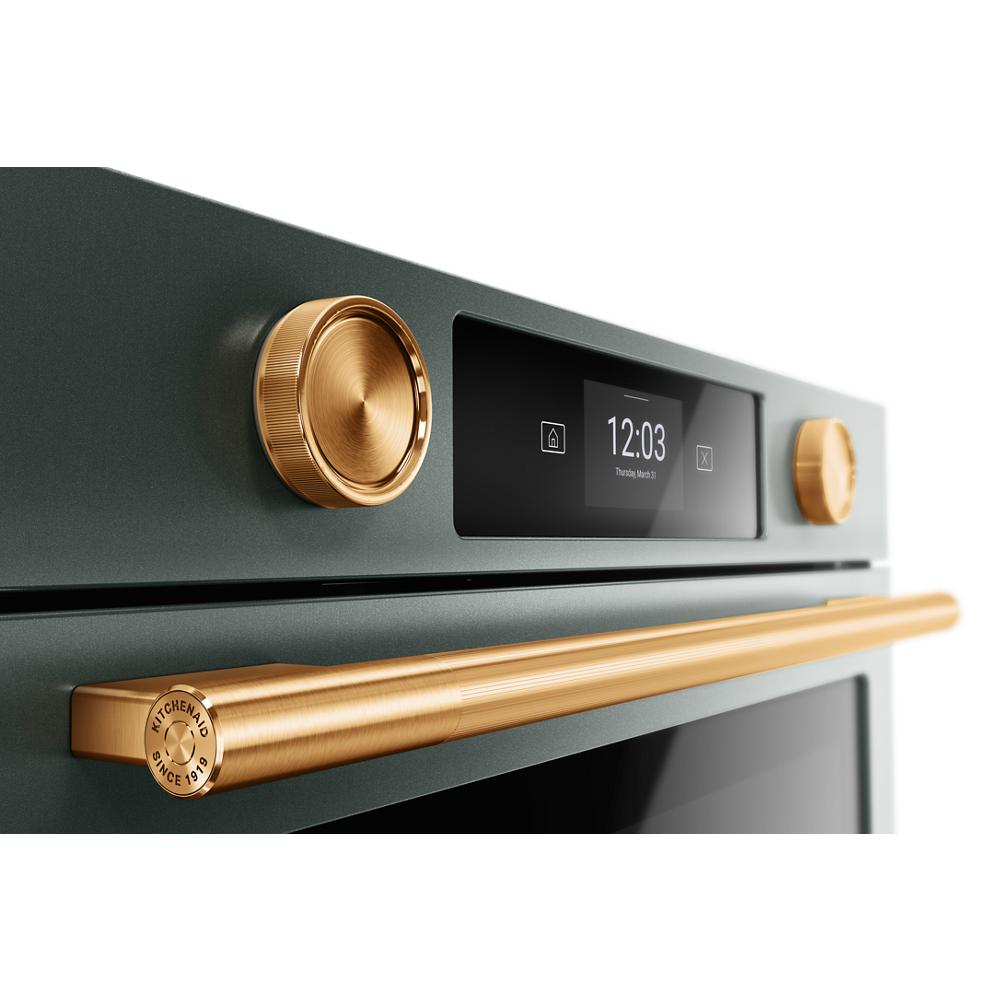Close-up of green smart electric wall oven with gold-tone knobs and handle showing digital clock and touch display in kitchenware collection