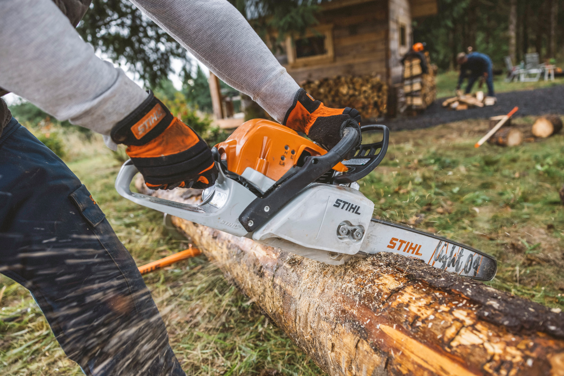 Orange and white fuel-efficient chainsaw cutting a large log outdoors for tools and home improvement use