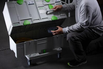 Person organizing power tools inside a large white and green Festool interlocking tool storage box on wheels
