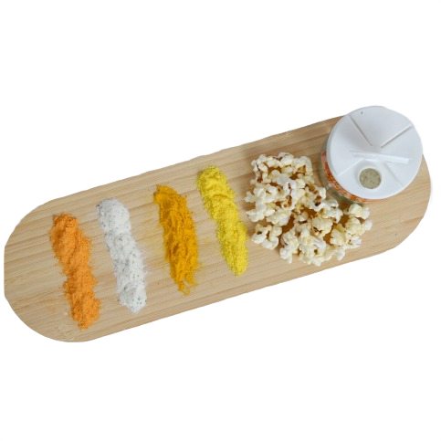 Four vibrant seasoning powders arranged beside popcorn and a seasoning shaker on a wooden board in food and beverage collection