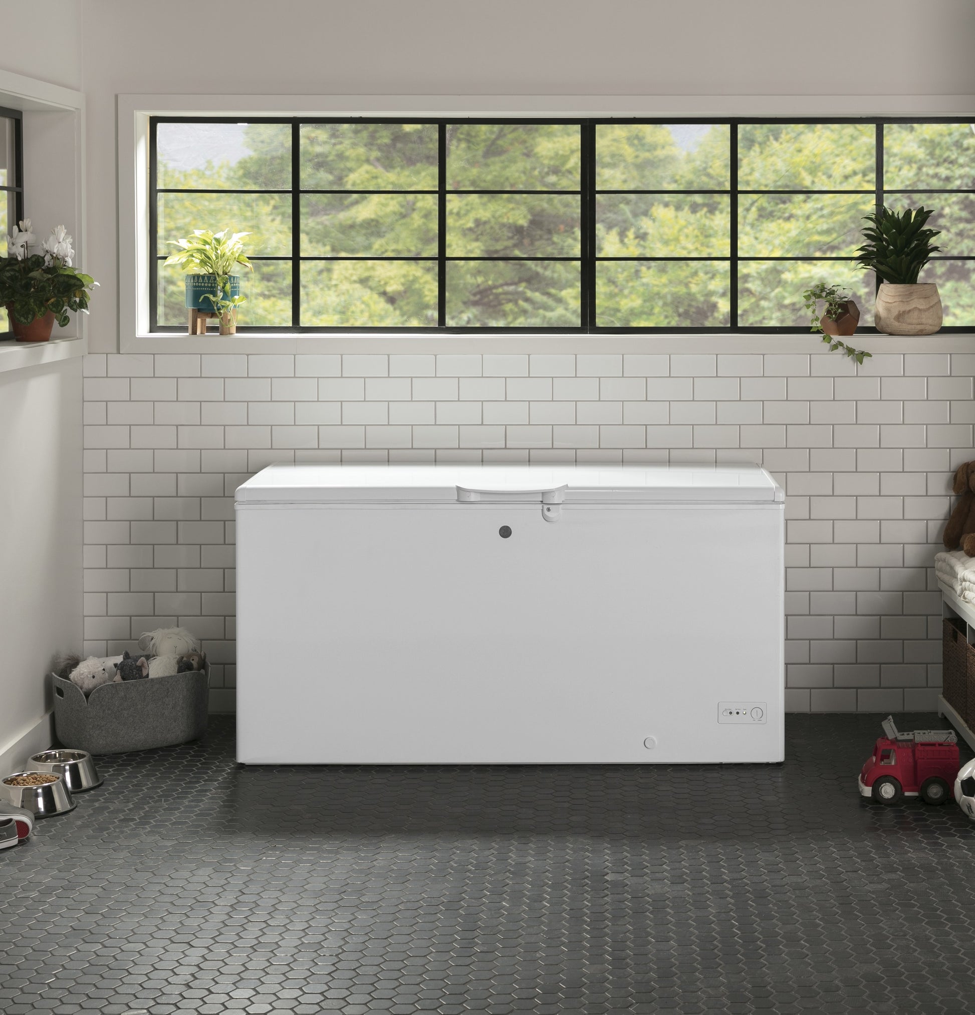 White manual defrost chest freezer in kitchen setting with tiled backsplash and window above, home appliance in freezer category