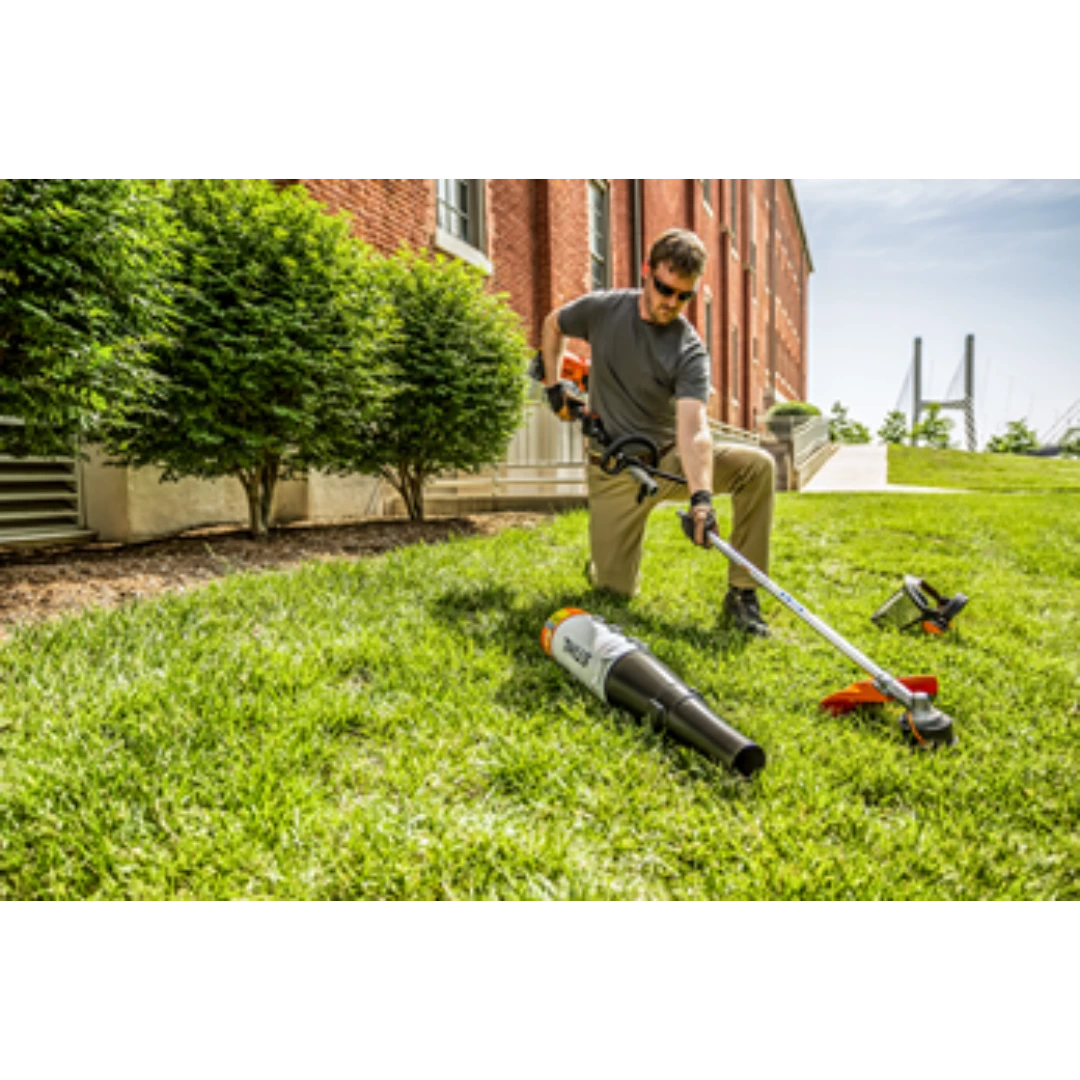 Man kneeling on lawn using a lightweight cordless KombiMotor attachment for outdoor tools and home improvement tasks