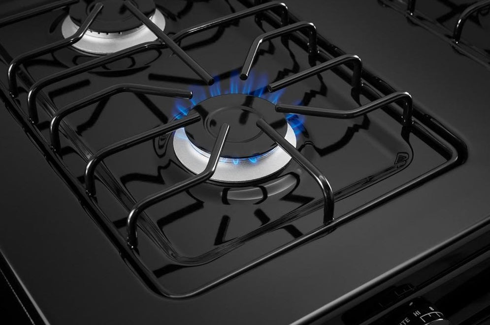 Close-up of black Amana gas cooktop burner with blue flame and sturdy cast iron grates from Ranges & Cooktops collections