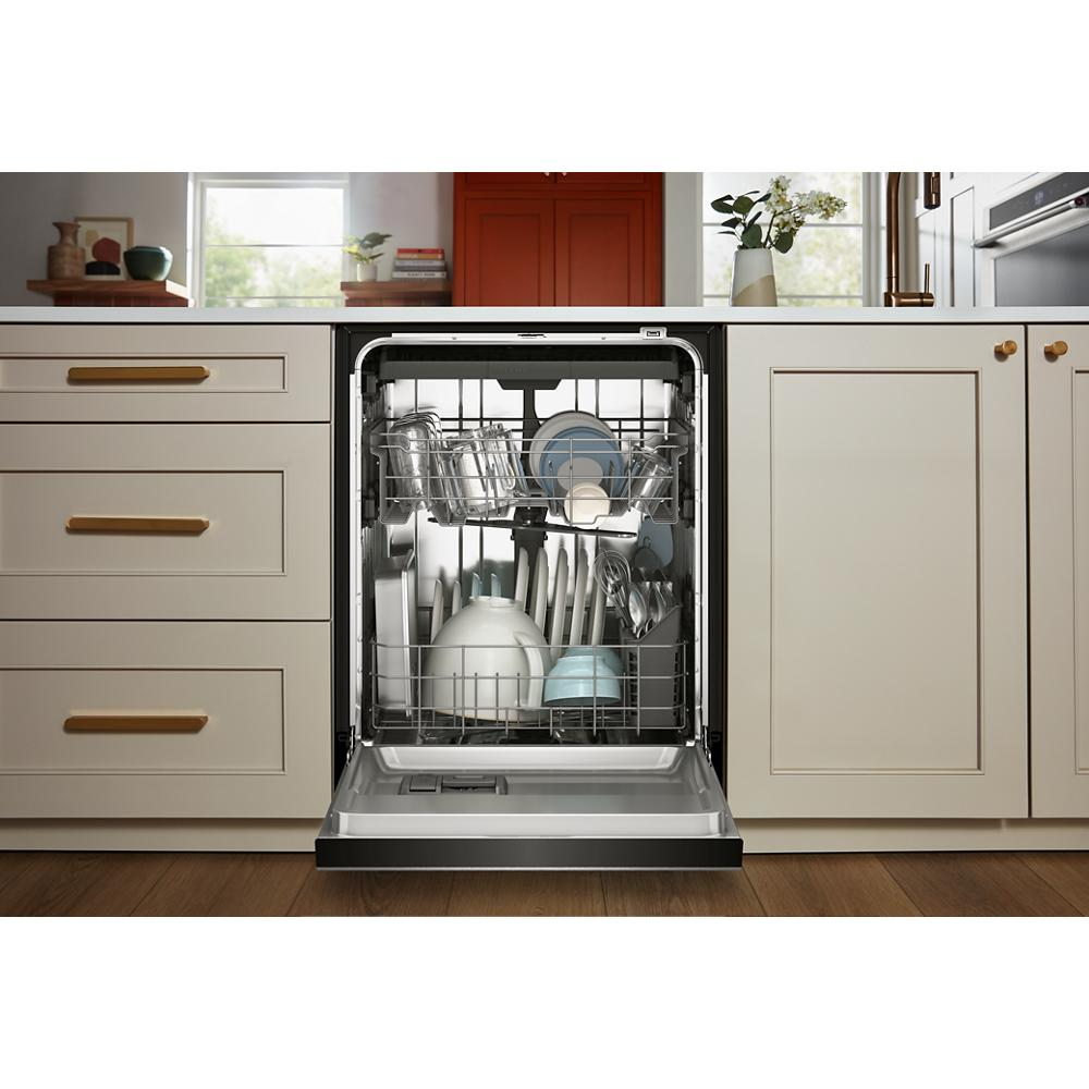 Open dishwasher integrated into kitchen cabinetry with loaded racks featuring plates, glasses, and utensils