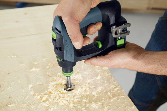 Person using a Festool cordless drill with drill bit making hole in wood with wood shavings for home improvement
