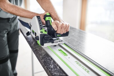 Person using Festool track saw with guide rail on black countertop for precise woodworking cuts in tool accessories collection