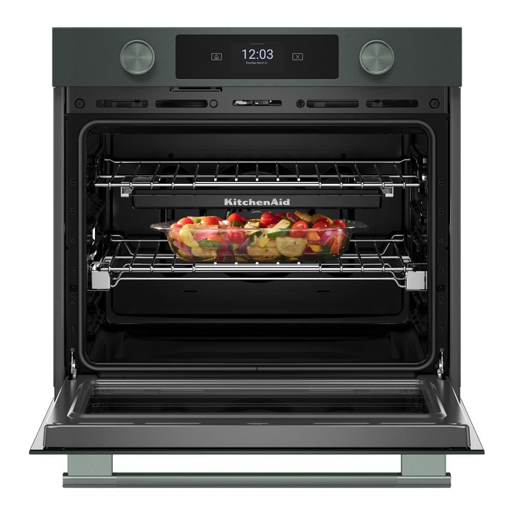 Open juniper smart electric wall oven with digital display and backlit knobs, cooking mixed vegetables inside