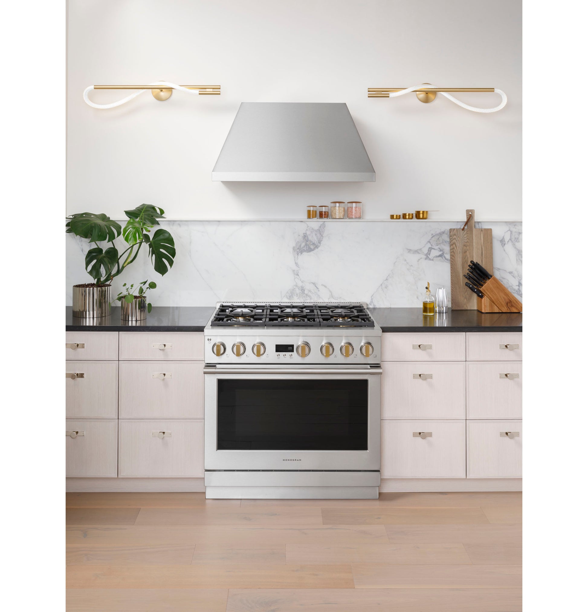 Stainless steel dual-fuel professional range with six burners centered between light cabinetry and marble backsplash in kitchen collection