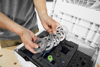 Person organizing metal routing accessory rings inside a foam-inserted storage case for woodworking tools and home improvement projects