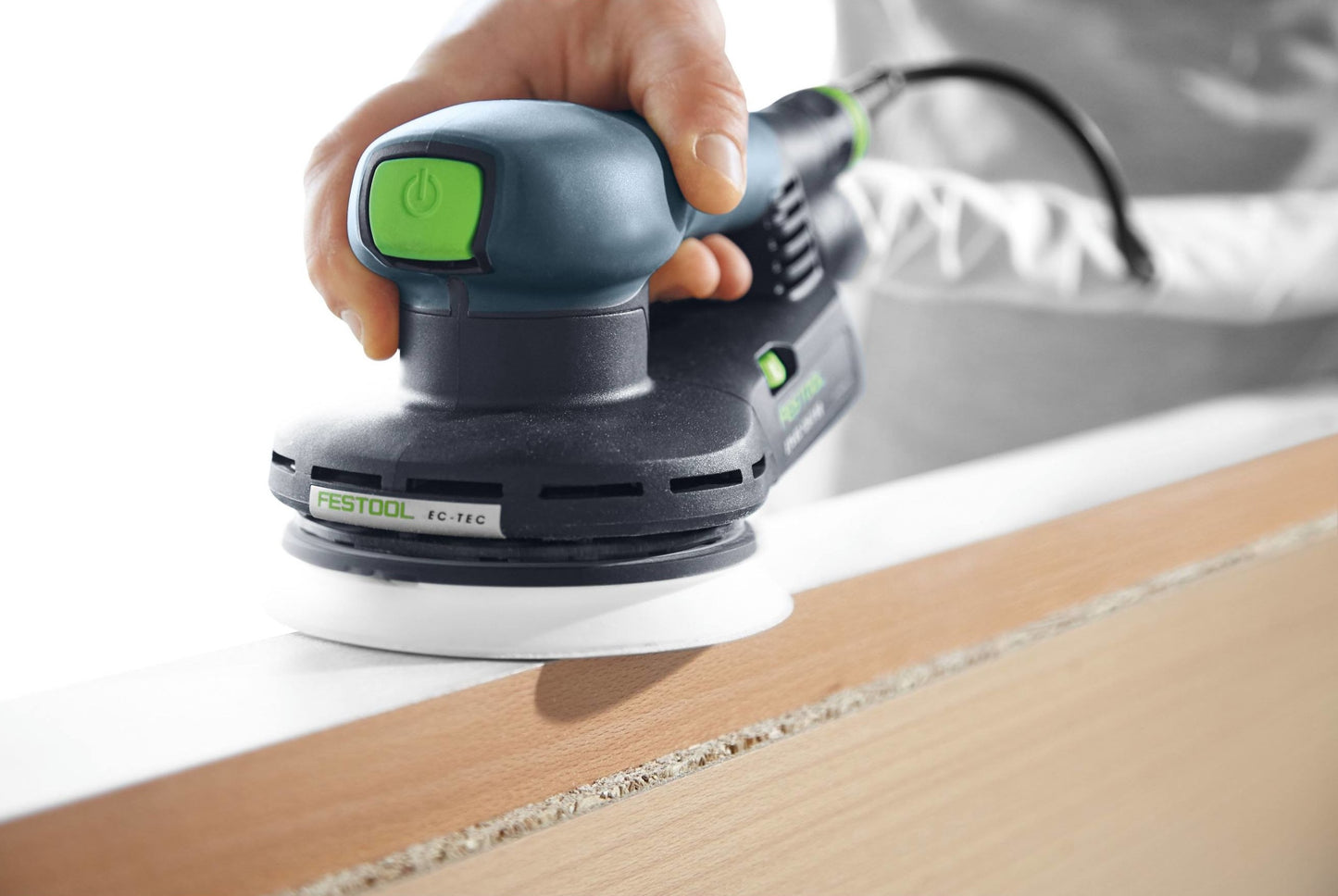 Hand-held random orbit sander smoothing edge of light wood panel in a woodworking tools and power tools setting