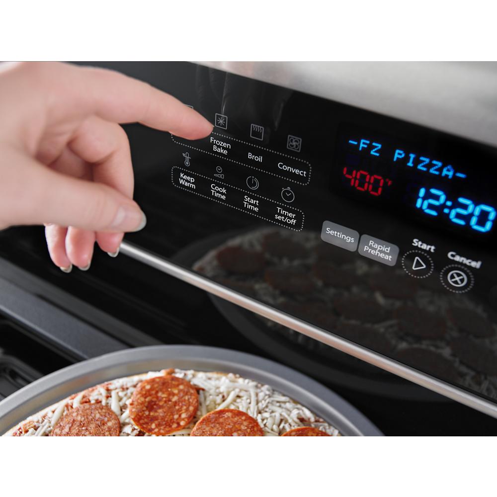 Finger pressing digital control panel on electric double oven set to 400 degrees cooking frozen pizza in stainless steel kitchen range