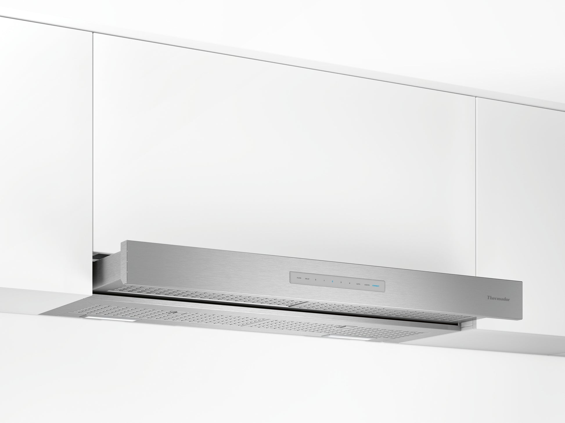 Stainless steel custom insert range hood installed under white cabinetry in modern kitchen setting
