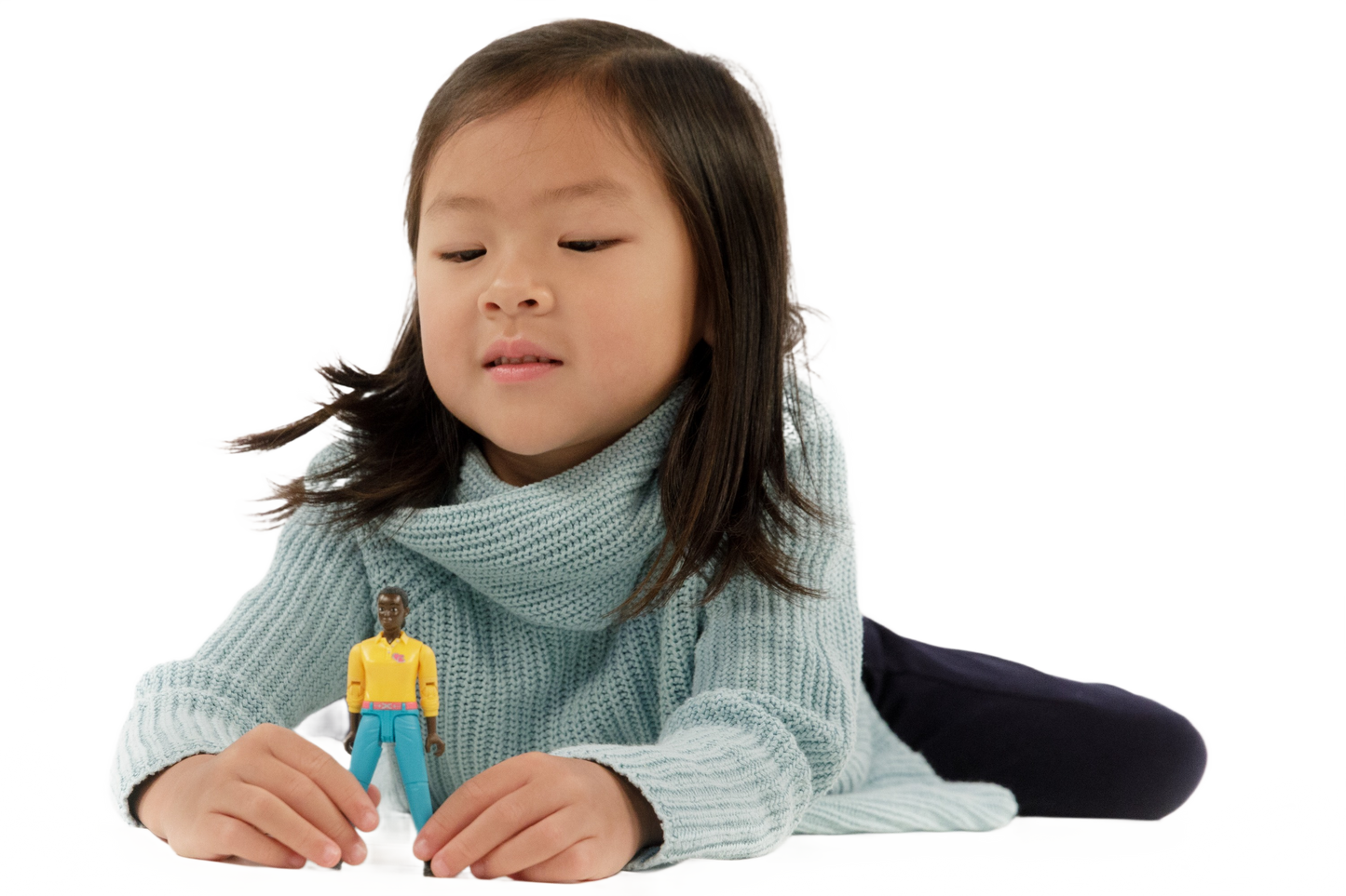 Girl lying down playing with Bruder woman action figure wearing turquoise jeans and yellow top from toy collection
