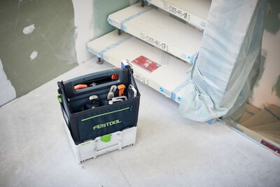 Black and green Festool tool bag with multiple compartments on a workshop floor for tool storage and organization