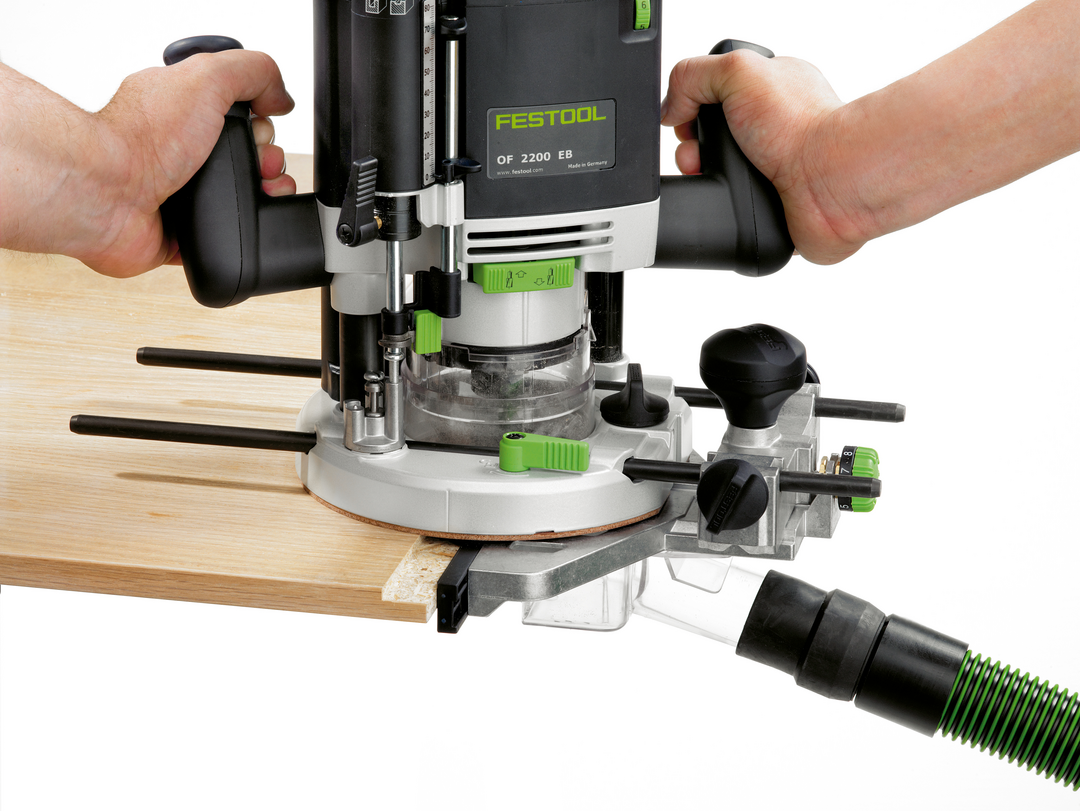 Hands guiding Festool OF 2200 EB router on light wood with dust extraction hose attached for woodworking tools collection