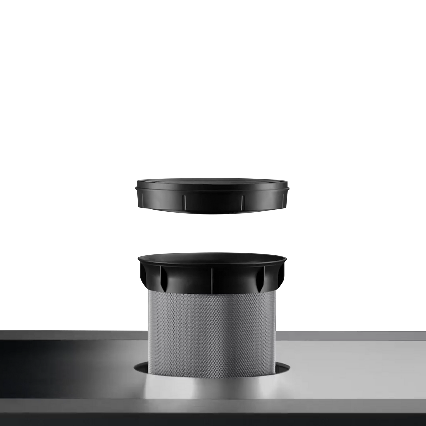 Close-up of the removable filter basket and cover on a sleek induction downdraft cooktop surface