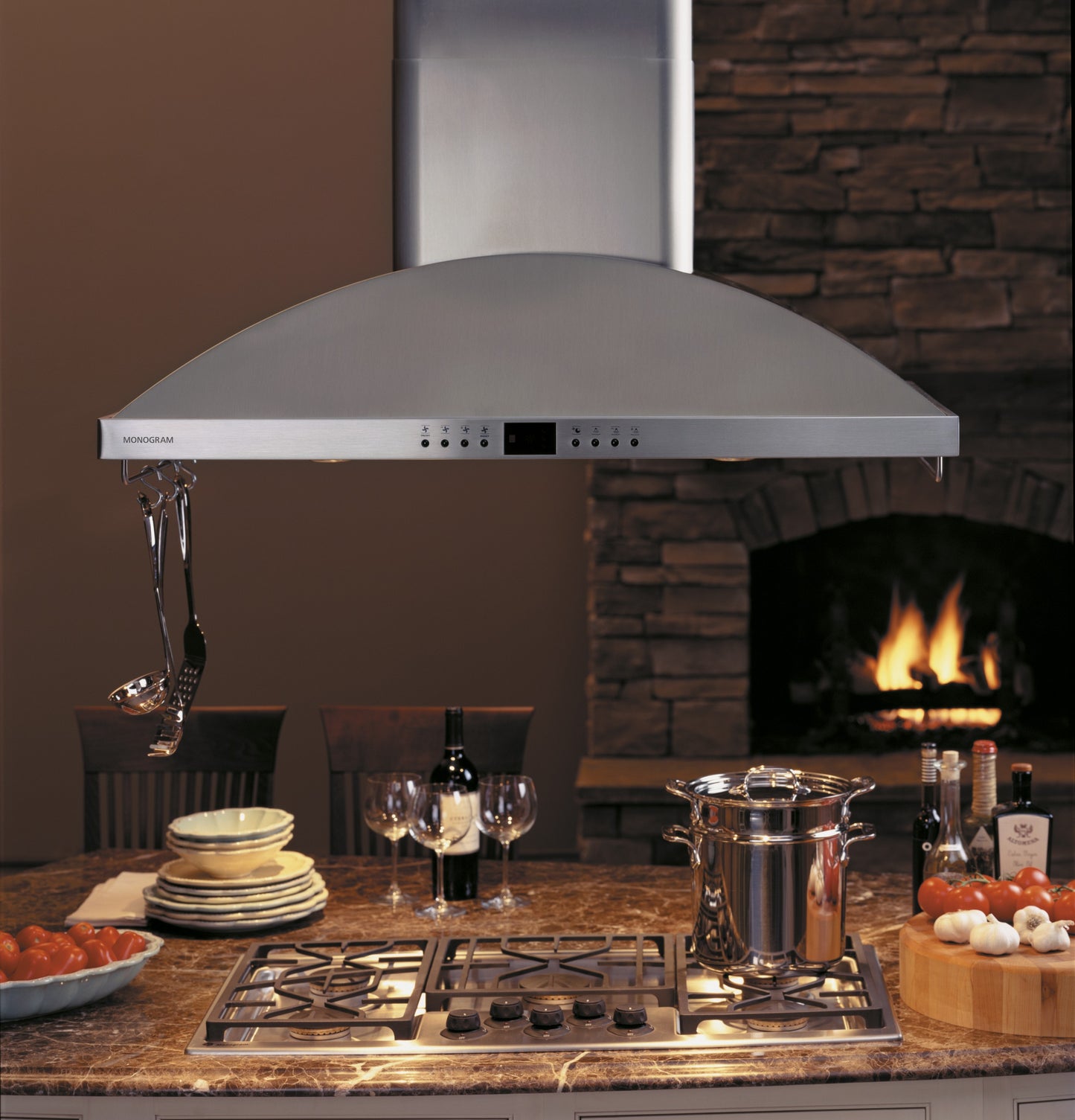 Stainless steel high-performance island hood with digital controls above gas cooktop in kitchen appliances collection