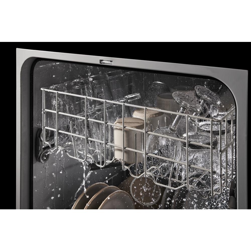 Water spraying inside a dishwasher rack filled with glassware and dishes during a cleaning cycle for kitchen appliances