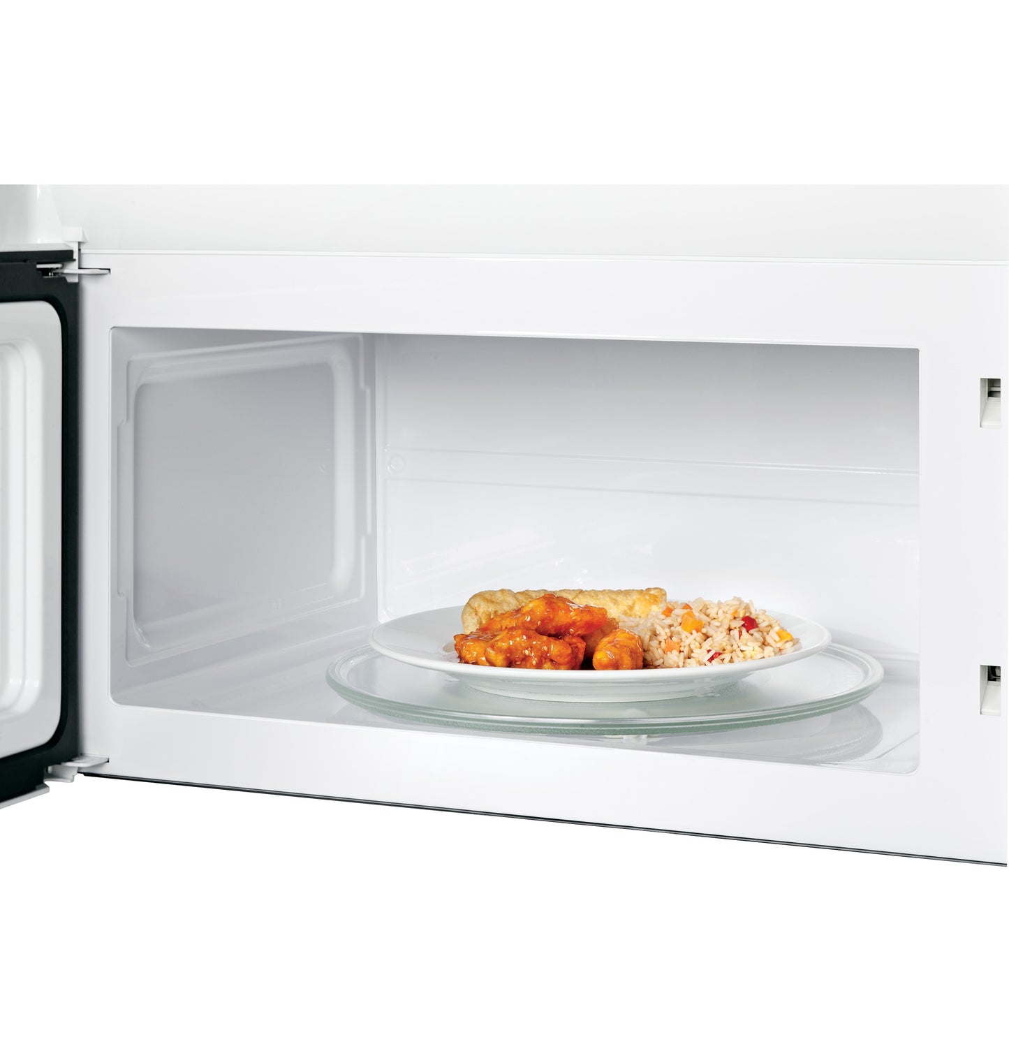 Interior view of white over-the-range microwave oven with glass turntable heating a plate of food from kitchen appliances collection