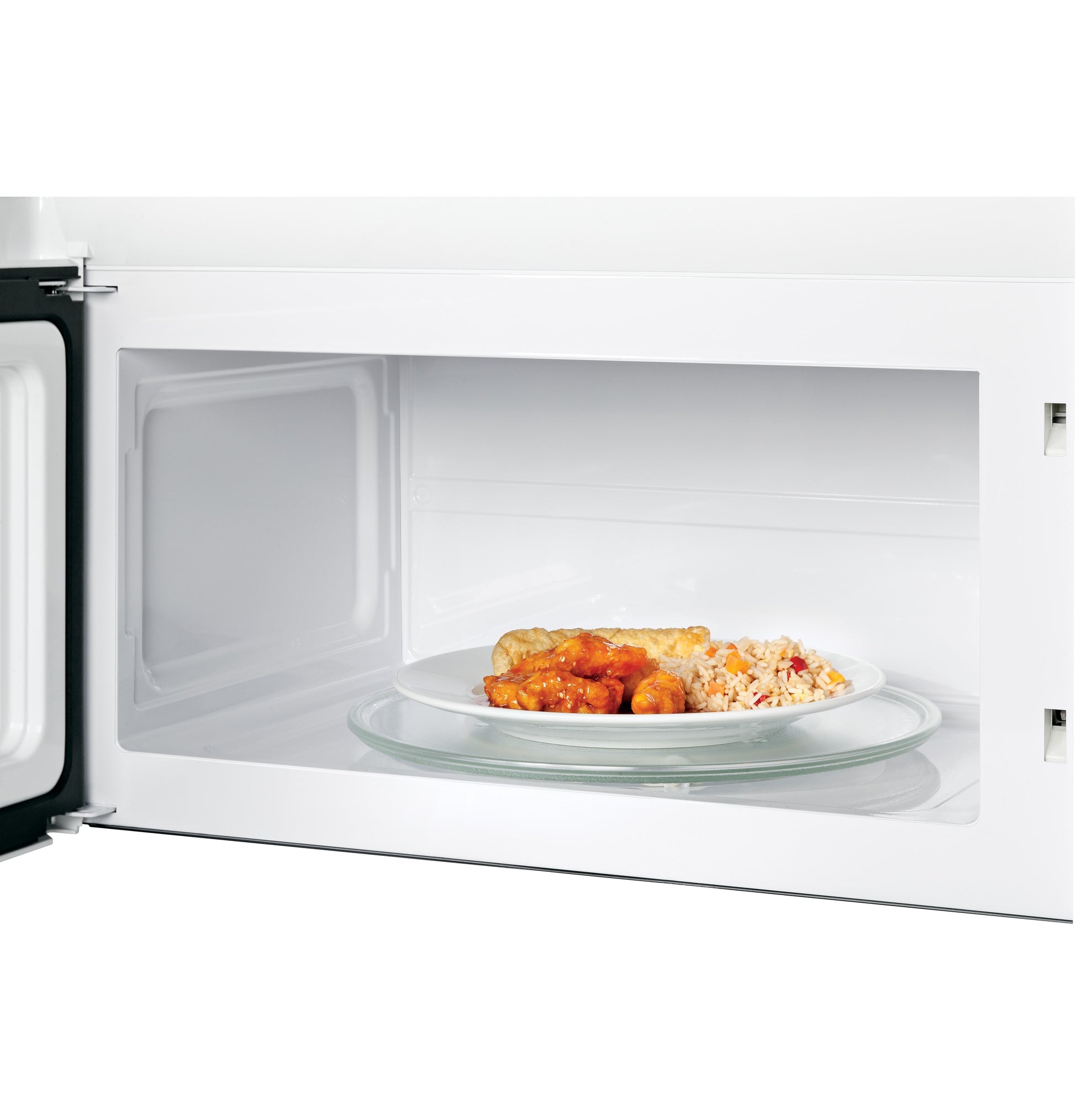 Interior view of white over-the-range microwave oven with glass turntable heating a plate of food from kitchen appliances collection
