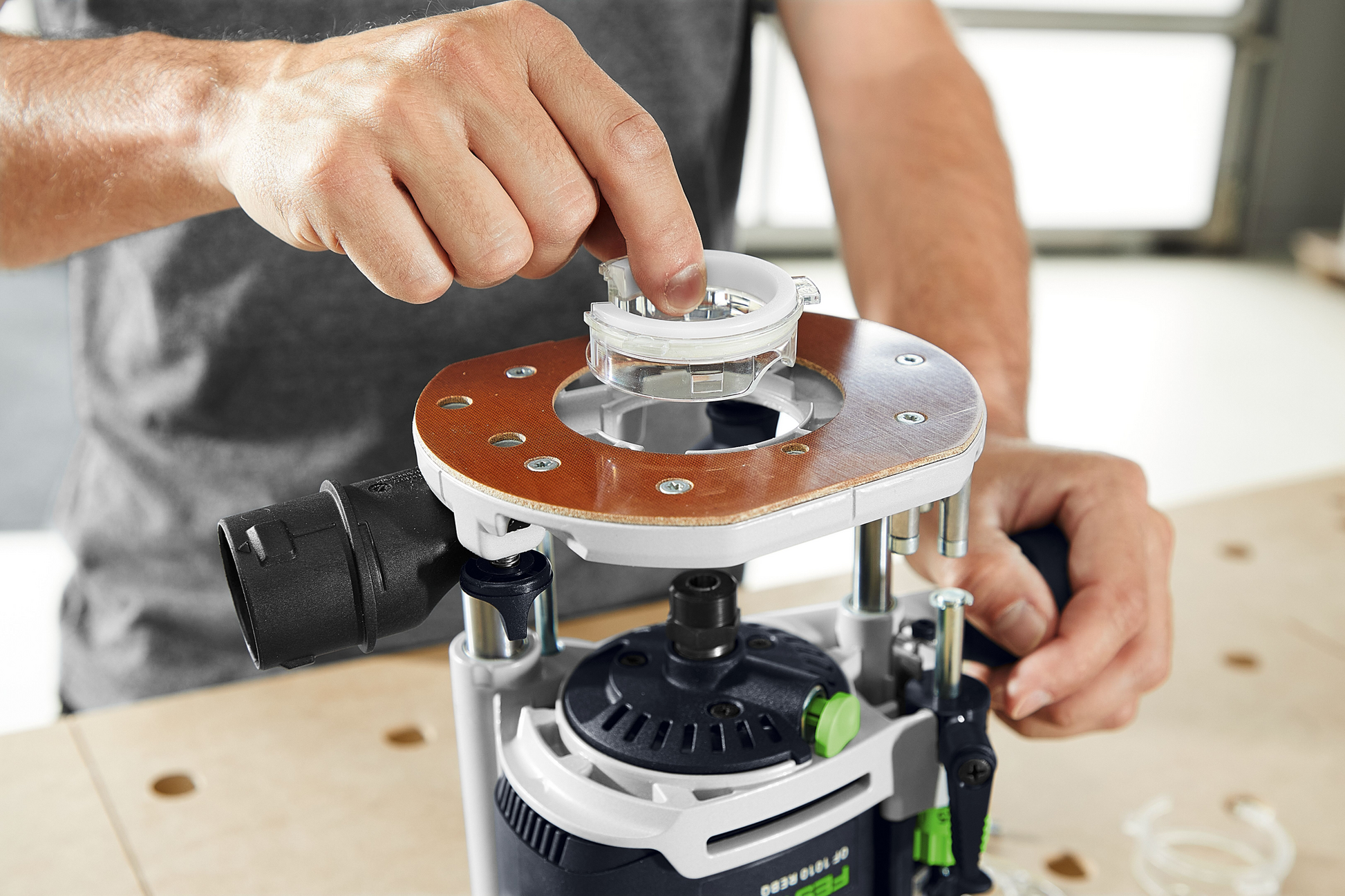 Person adjusting a Festool light module with integrated LED ring on a woodworking router tool accessory