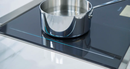 Dark gray induction cooktop surface mount with stainless steel saucepan heating on smooth glass surface