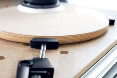 Close-up of adjustable clamp securing round wooden piece on multifunction woodworking table surface