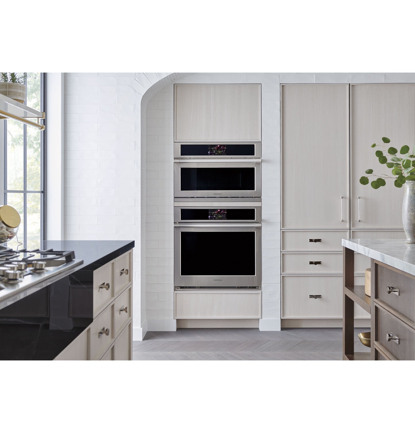 Built-in stainless steel wall oven unit integrated into modern kitchen cabinetry with light wood finishes and a gas cooktop nearby