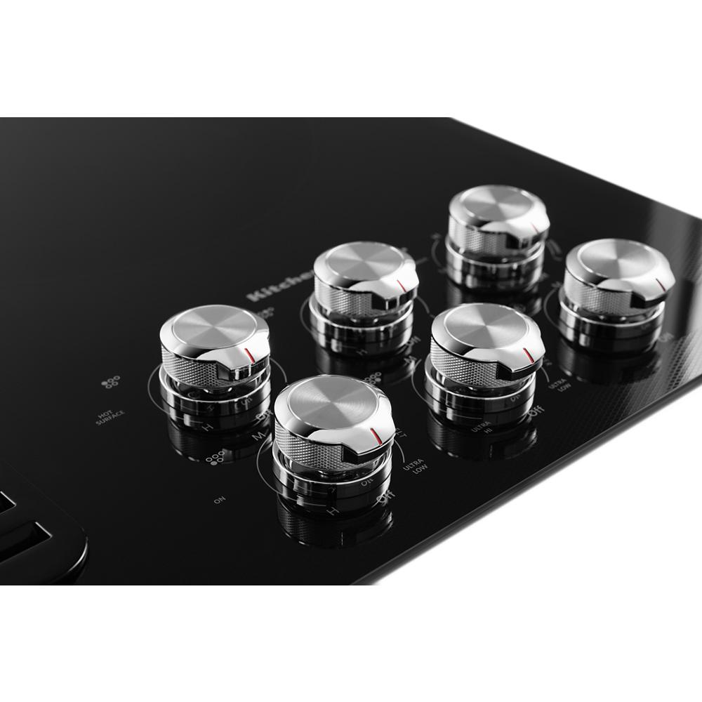 Black electric cooktop featuring five stainless steel control knobs from KitchenAid appliances collection