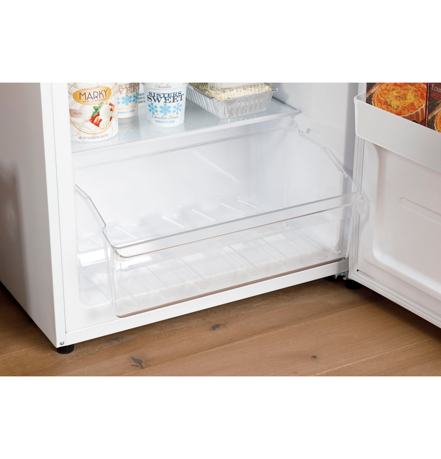 Interior drawer open in upright freezer showing clear storage bin and frozen food on top shelf in kitchen appliance setting