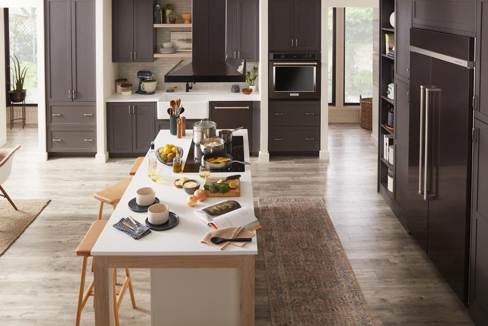 Modern kitchen with dark cabinetry, large island, 36-inch canopy hood, and stainless steel appliances from KitchenAid collection