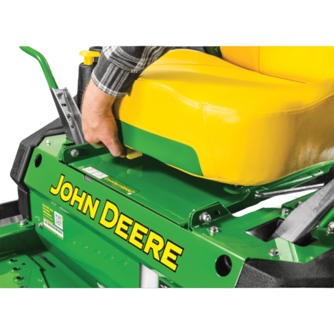Close-up of a green and yellow lawn mower with a person adjusting the seat for comfort in home improvement tasks