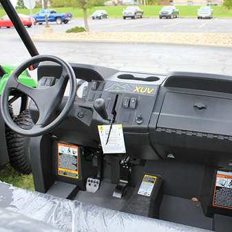 Interior view of a green mid-size utility vehicle featuring dashboard controls and steering wheel for outdoor work use