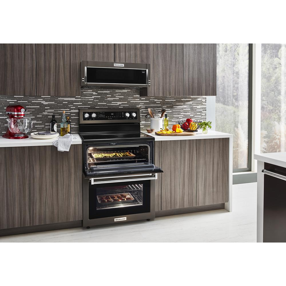 Modern double oven electric range with five burners installed in a contemporary kitchen featuring dark wood cabinets and mosaic backsplash