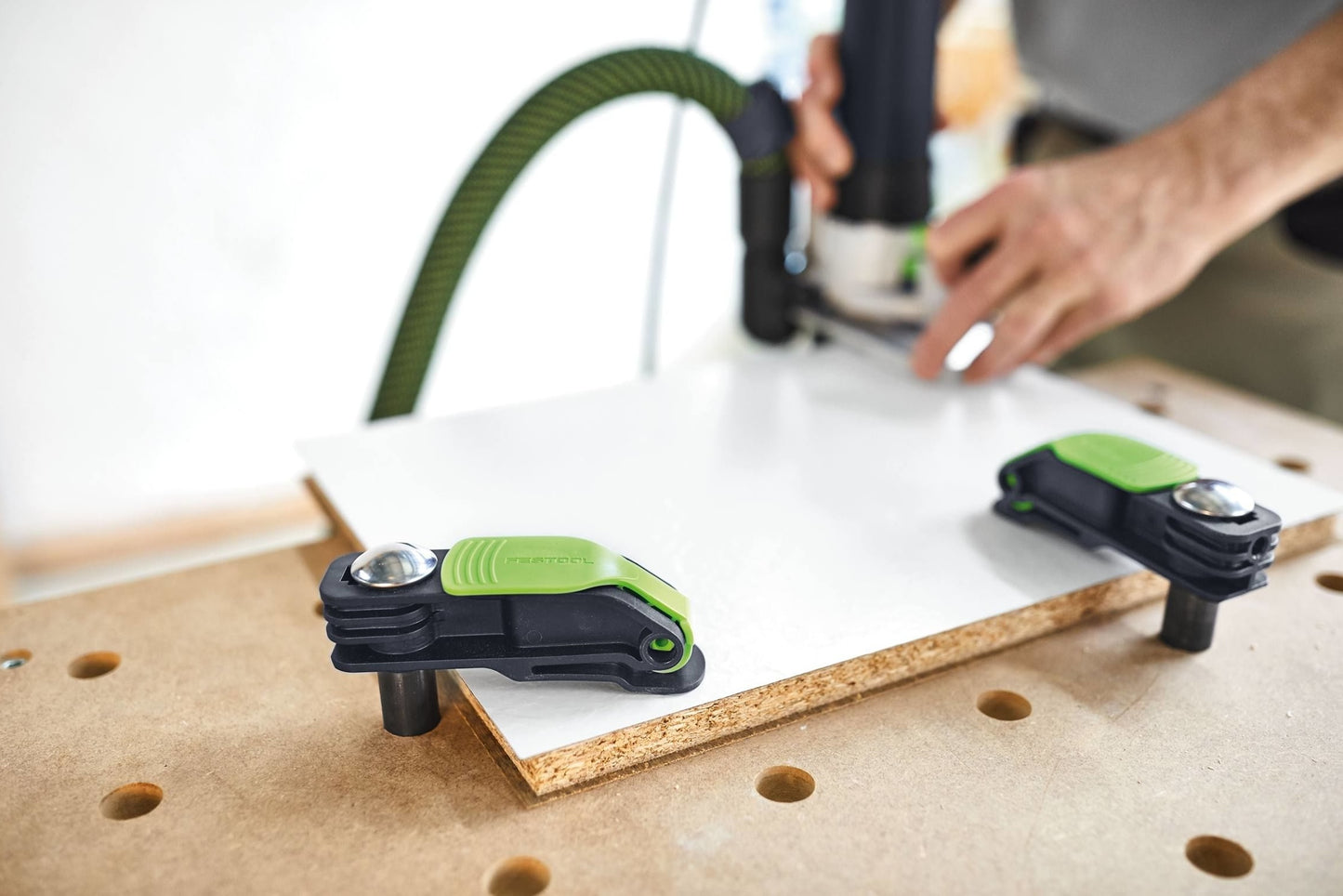 Festool quick clamps securing wood panel on workbench while hands operate power tool for home improvement