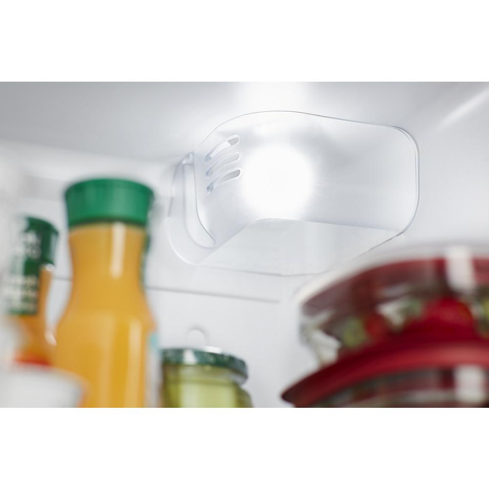 LED light illuminating interior storage area with juice bottles and containers in refrigerator from kitchen appliances collection