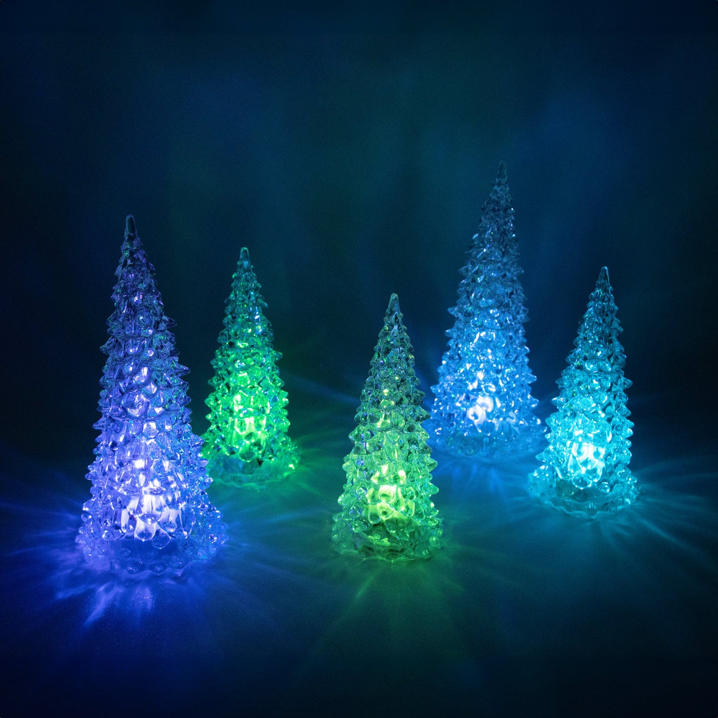 Set of five translucent decorative trees glowing in blue and green hues for ambient seasonal home accents