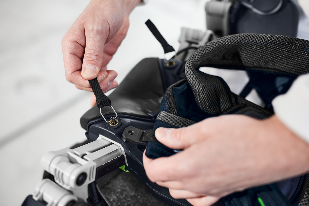Close-up of hands adjusting straps on a black ergonomic support harness in Festool tool accessories collection