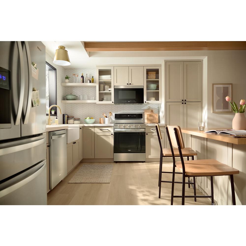 Bright kitchen with beige cabinetry, stainless steel stove and dishwasher, and air fry over-the-range microwave installed
