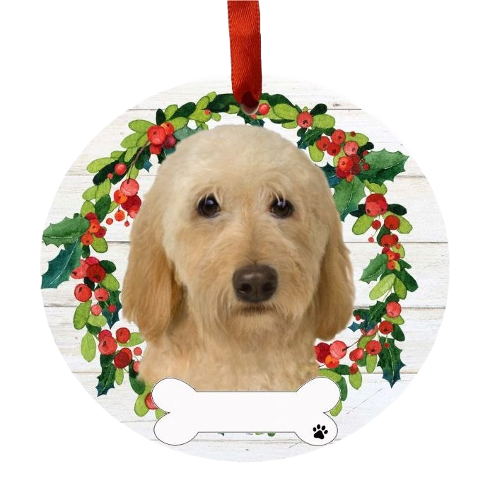 Round Christmas ornament with cream Labradoodle portrait inside a festive berry and greenery wreath hanging by a red ribbon
