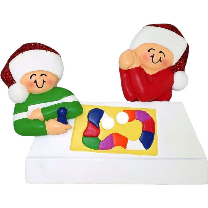 Holiday ornament showing two smiling figures in festive hats playing a colorful family board game decoration
