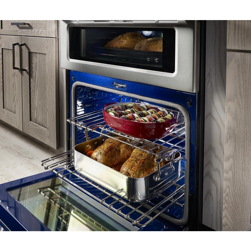 blue interior gas double oven with multiple dishes baking on racks in modern kitchen setting