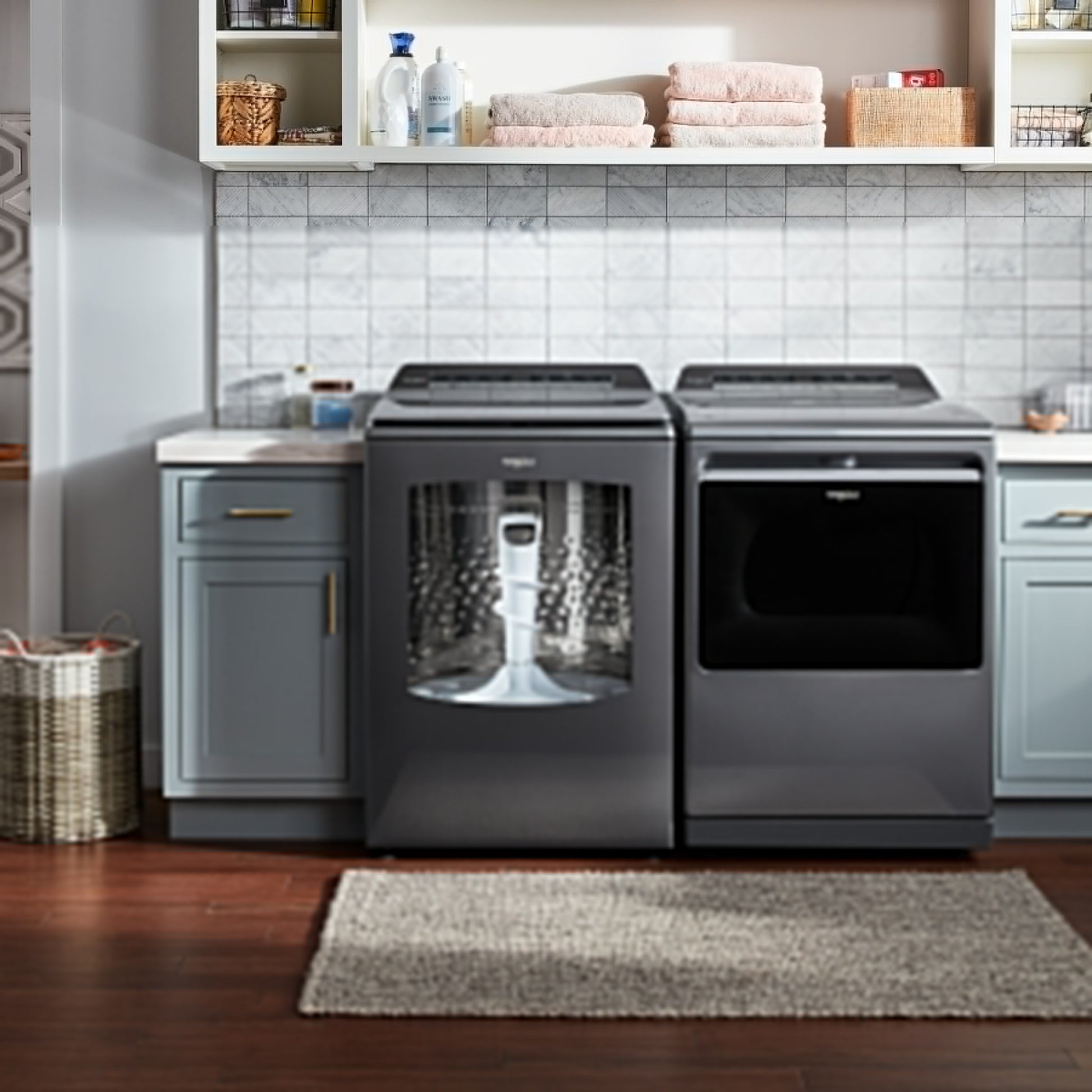 Laundry room with dark gray top load washer and matching gas dryer on wood floor in modern appliances setting
