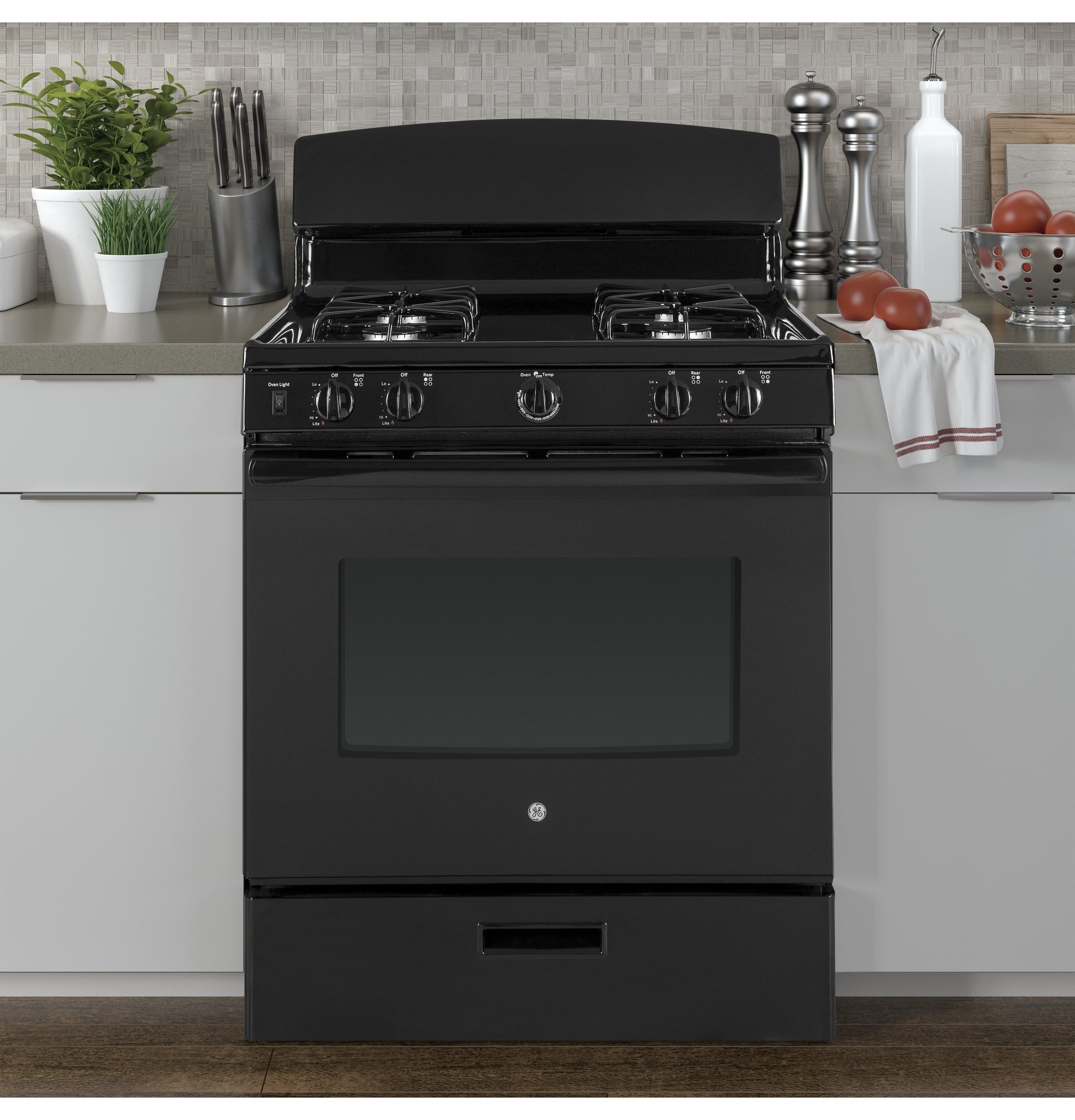 Black free-standing gas range with four burners in modern kitchen setting with countertop decor and backsplash tiles